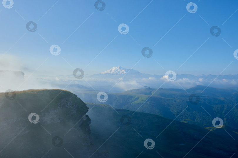 Скачать Эльбрус на восходе солнца, туман и облака на переднем плане. Перевал Гум-Баши, Северный Кавказ, Россия фотосток Ozero