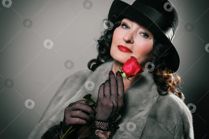 Скачать стильная женщина в шубе, шапке и перчатках держит в руках у губ красную розу фотосток Ozero