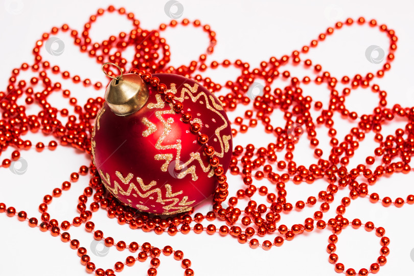 Скачать красный рождественский шар и гирлянда из бисера на белом фоне фотосток Ozero