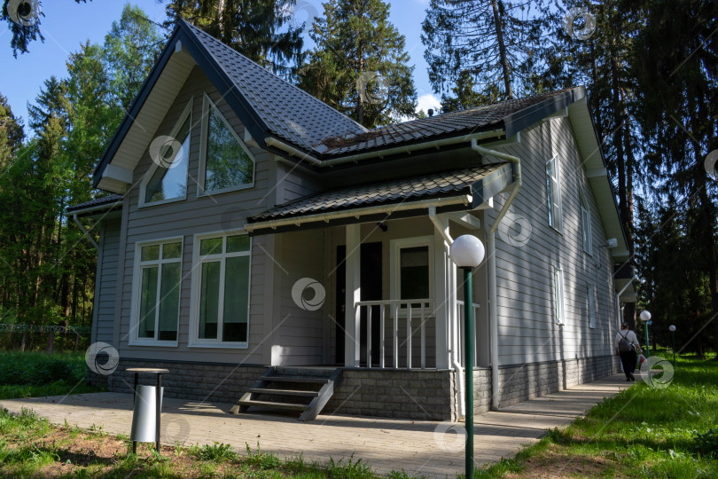 Скачать Внешний вид современного дома с верандой, отделанной серым сайдингом фотосток Ozero