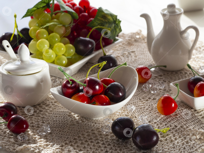 Скачать Красные и зеленые гроздья винограда, вишни, яблок лежат на белом блюде. фотосток Ozero