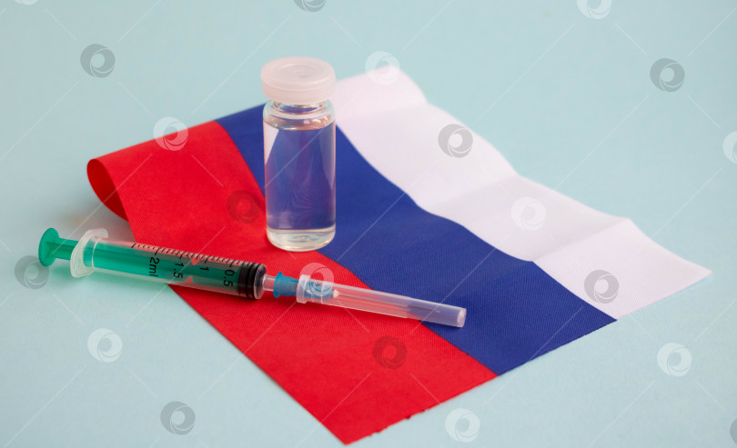 Скачать Вакцина и шприц для инъекций изображены на маленьком флаге России. Для профилактики, иммунизации и лечения коронавирусной инфекции. Концепция медицины и здравоохранения фотосток Ozero