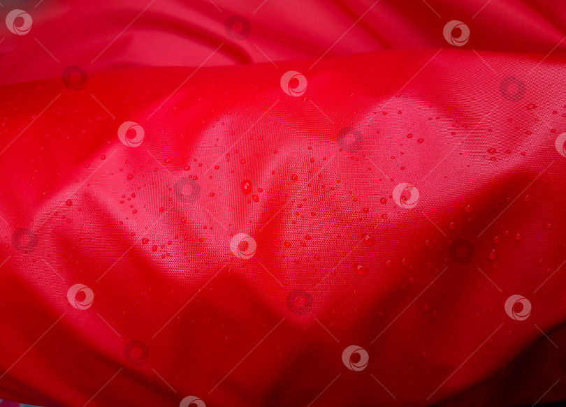 Скачать Крупные капли воды на красном текстиле с водонепроницаемым эффектом. Водоотталкивающая пропитка. Капли текстуры на ткани фотосток Ozero