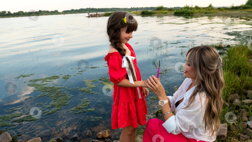 Скачать Мама и маленькая дочка прогуливаются у озера или пруда фотосток Ozero