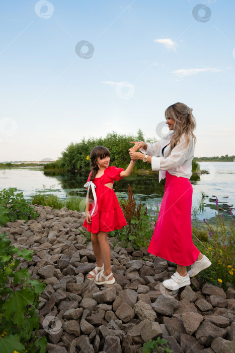 Скачать Мама и маленькая дочка прогуливаются у озера или пруда фотосток Ozero