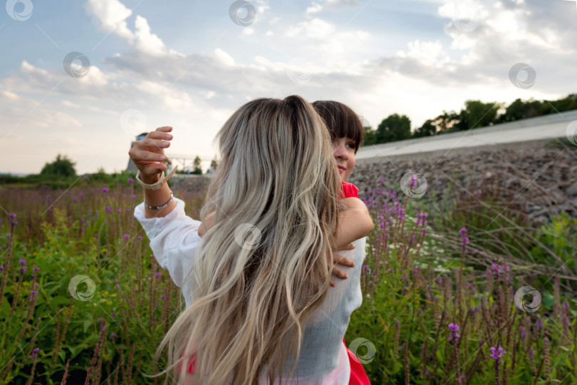 Скачать Мама и маленькая дочка обнимаются среди луговых цветов фотосток Ozero