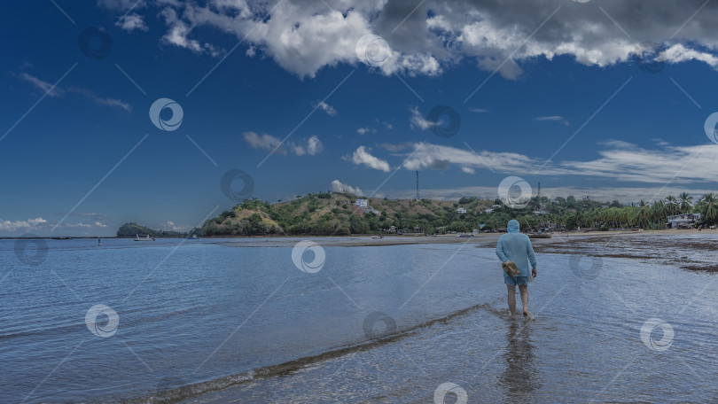 Скачать Мужчина идет по воде на берегу океана фотосток Ozero