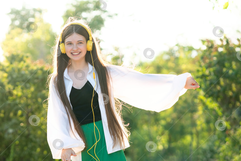 Скачать Девочка-подросток слушает музыку и танцует в наушниках на открытом воздухе фотосток Ozero