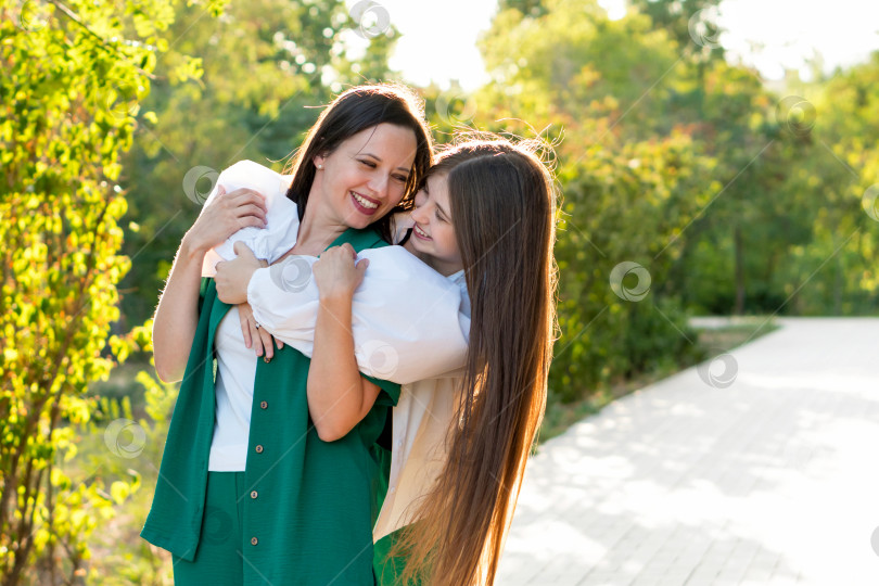 Скачать Мама и дочь-подросток обнимаются на прогулке в парке фотосток Ozero