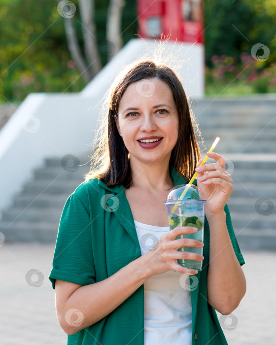 Скачать Женщина пьет безалкогольный напиток на прогулке в парке фотосток Ozero
