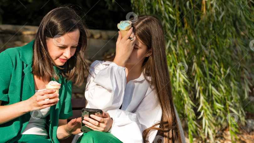 Скачать Мама и дочь-подросток едят мороженое на прогулке фотосток Ozero