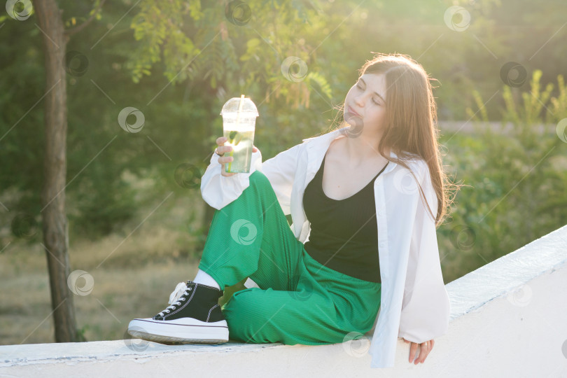 Скачать Девушка-подросток пьет безалкогольный напиток на прогулке в парке фотосток Ozero