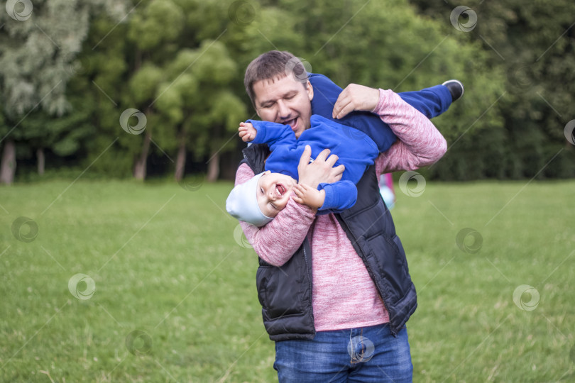 Скачать Мужчина играет со своим сыном на зеленой лужайке. Живите эмоциями отца и сына. фотосток Ozero