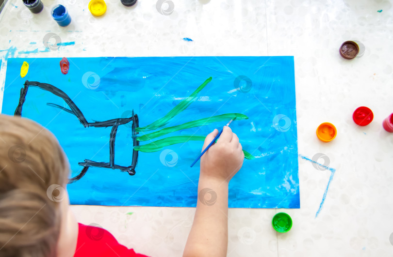 Скачать Ребенок рисует яркую картинку. Крупные мазки краски на бумаге. фотосток Ozero