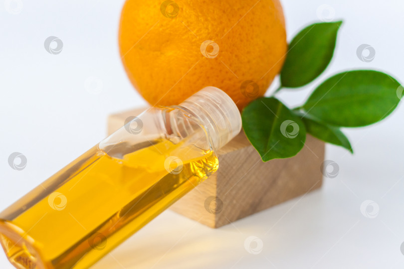 Скачать Апельсиновое масло для тела. Оранжевый цвет на деревянной подставке на белом фоне. Органическая СПА-косметика с растительными ингредиентами. фотосток Ozero