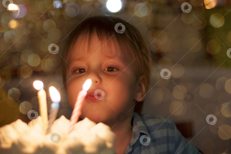 Скачать Милый мальчик задувает свечи в свой третий день рождения. День рождения ребенка. фотосток Ozero