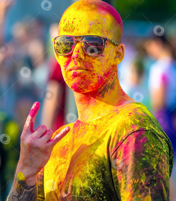 Скачать Череповец, Россия, 28 августа 2022 года Молодой человек в очках показывает жест козла, используемый фанатами рока и хэви-метала на вечеринке Holi color. фотосток Ozero