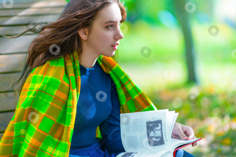 Скачать Молодая девушка, женщина читает книгу в парке и мечтательно смотрит вдаль. фотосток Ozero
