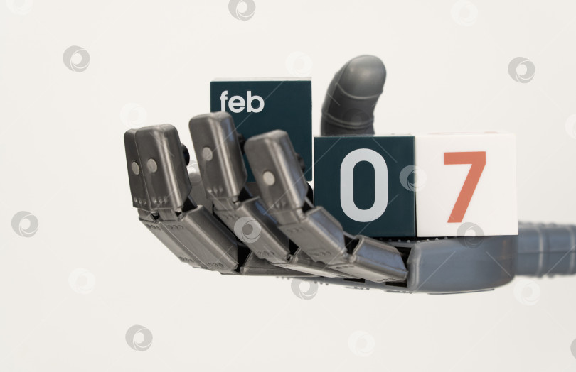 Скачать рука робота держит кубики с датой 07 февраля. крупный план, выборочный фокус. Всемирный день робототехники фотосток Ozero
