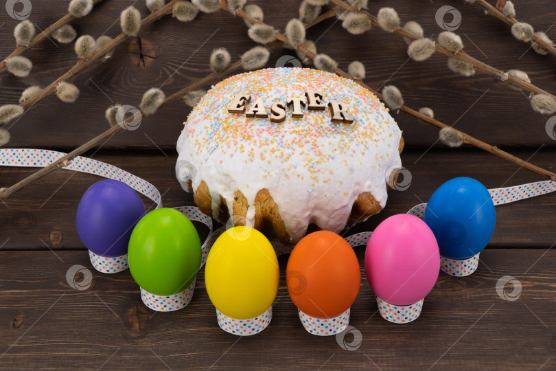 Скачать праздничный пирог с надписью "Пасха" и разноцветными яйцами на деревянных досках. Пасхальный хлеб и верба на винтажном фоне. фотосток Ozero