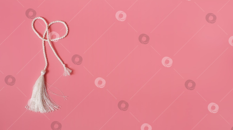 Скачать Концептуальный плакат: Белая шелковая кисточка, выделенная на розовом фоне для создания графических концепций фотосток Ozero