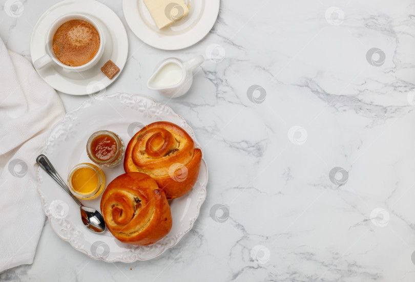 Скачать Две булочки с изюмом, джемом и медом на белой тарелке на мраморном фоне на завтрак. Кофе, молоко, масло на столе. Выборочный фокус, вид сверху и пространство для копирования фотосток Ozero