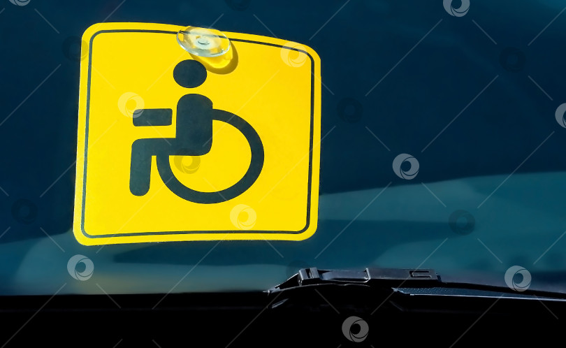 Скачать Знак для инвалидов на стекле коричневого автомобиля. Инвалид в машине. Перевозка людей с ограниченными возможностями. фотосток Ozero