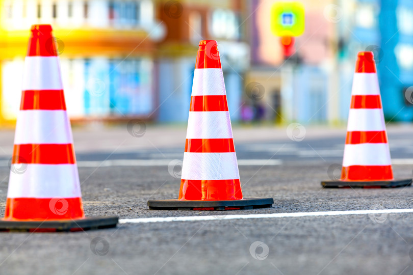 Скачать Оранжевый дорожный барьер с дорожным конусом в выборочном фокусе на городской улице во время дорожно-строительных работ. фотосток Ozero