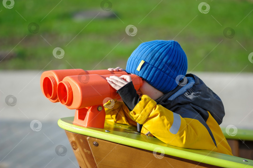 Скачать Маленький мальчик смотрит в бинокль, играя на корабле на детской игровой площадке. Концепция далеких путешествий, приключений и детских грез. фотосток Ozero