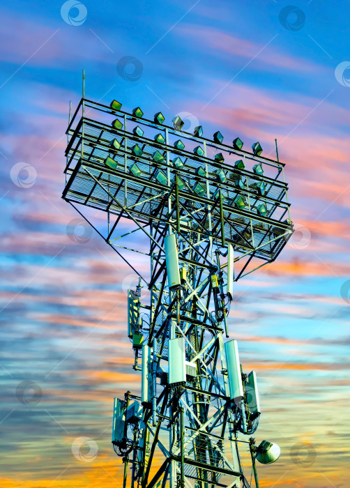 Скачать Точечная световая башня на фоне закатного вечернего неба, подсветка стадиона или арены снаружи. фотосток Ozero