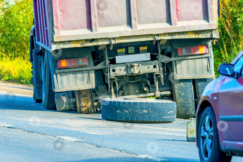 Скачать В результате аварии повреждена ступица колеса и шина грузовика. Сломанный грузовик на обочине дороги, ожидающий технического обслуживания. фотосток Ozero
