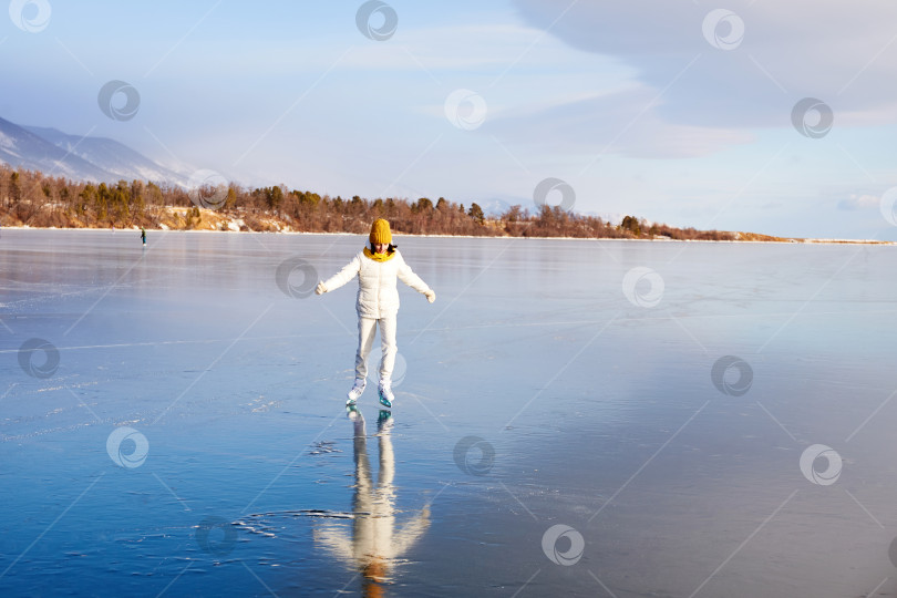 Скачать Молодая спортивная девушка катается на коньках по прозрачному льду замерзшего озера Байкал. фотосток Ozero