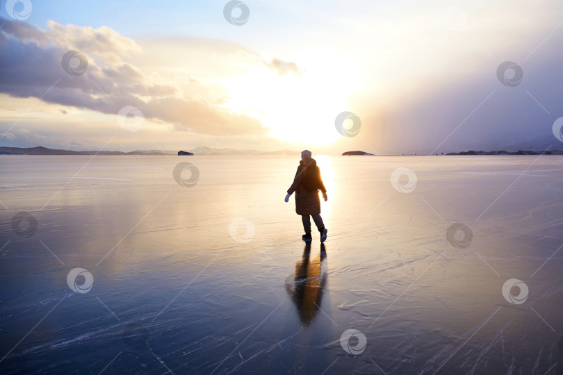 Скачать Молодая женщина любуется прекрасным закатом над озером зимой. фотосток Ozero