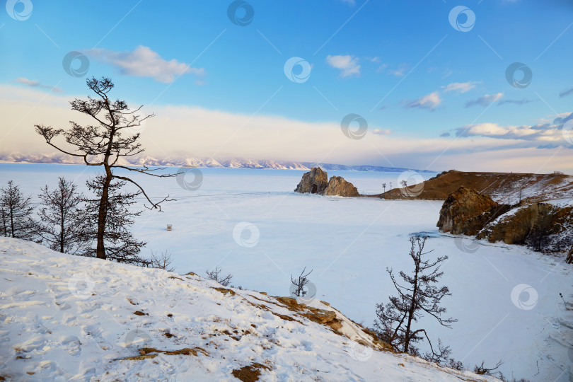 Скачать Вид на мыс Бурхан или скалу Шаманка на острове Ольхон зимой. Замерзшее озеро Байкал фотосток Ozero
