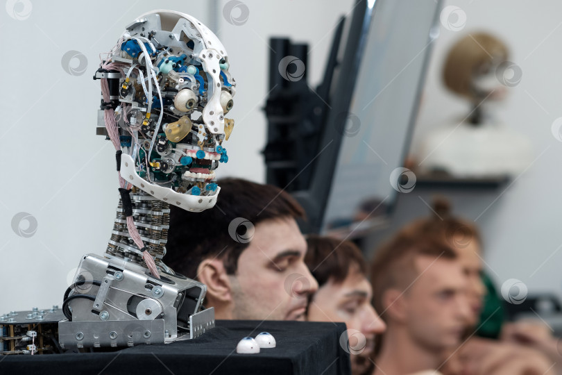 Скачать голова антропоморфного робота, способного имитировать эмоции, без внешней оболочки-кожи, на фоне различных сменных лицевых оболочек фотосток Ozero