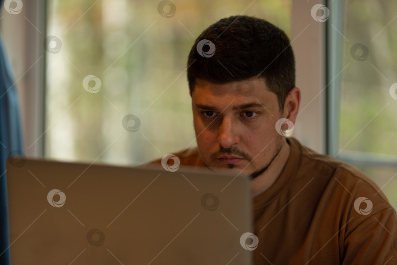 Скачать Мужчина работает на ноутбуке из дома, ведет небольшой бизнес фотосток Ozero