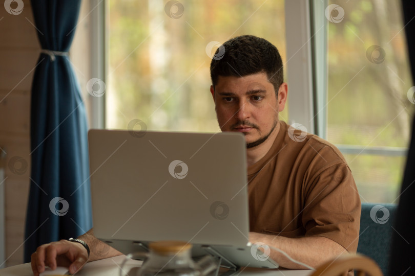 Скачать Мужчина работает на ноутбуке из дома, ведет небольшой бизнес фотосток Ozero