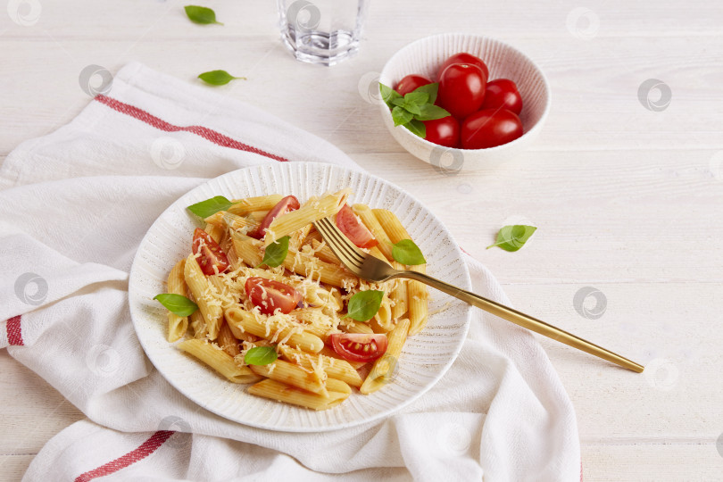 Скачать Паста пенне с помидорами и базиликом на светлом фоне. Традиционная итальянская кухня фотосток Ozero