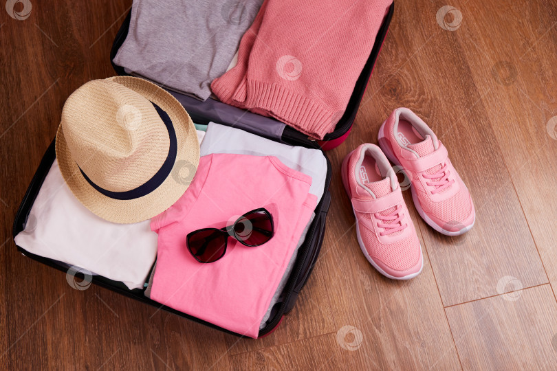 Скачать Открытый чемодан с женской одеждой и аксессуарами для предстоящей поездки. фотосток Ozero