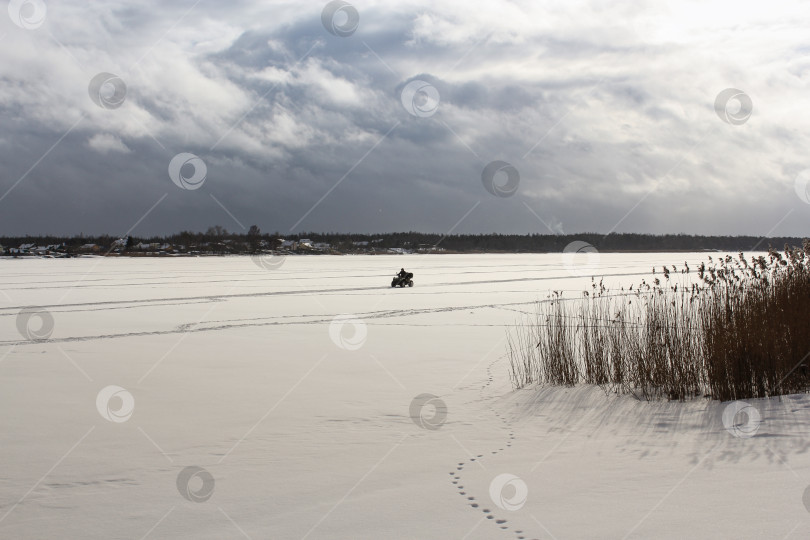 Скачать Мужчина на квадроцикле едет по замерзшей реке. фотосток Ozero
