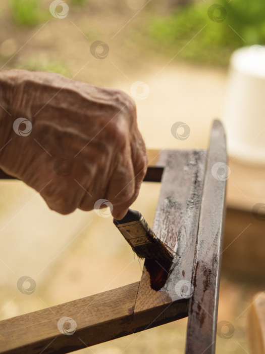 Скачать Процесс нанесения лака кистью для защиты древесины деревянной части стула от внешних воздействий. Реставрация старой мебели фотосток Ozero