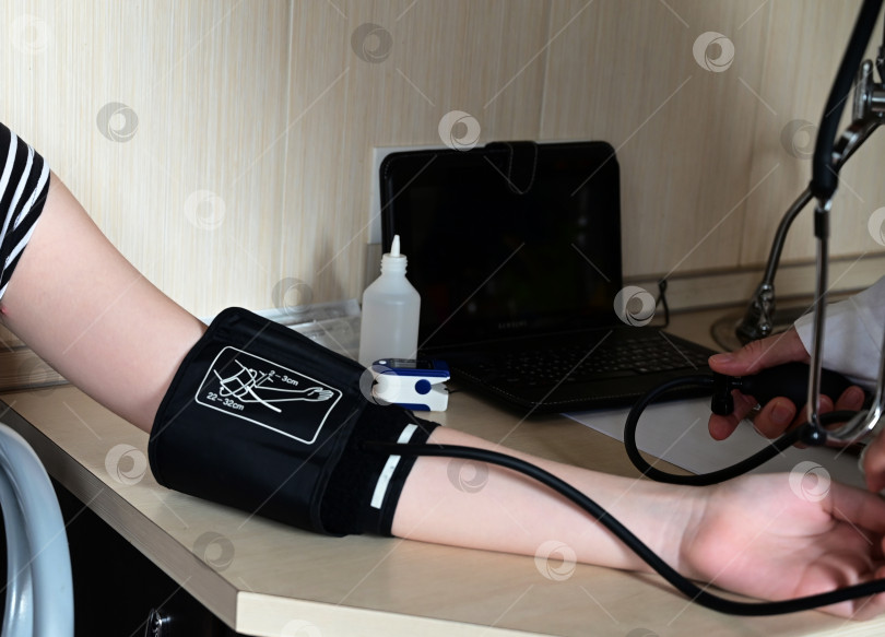Скачать Врач измеряет кровяное давление пациента в медицинском кабинете. Концепция медицинских услуг фотосток Ozero