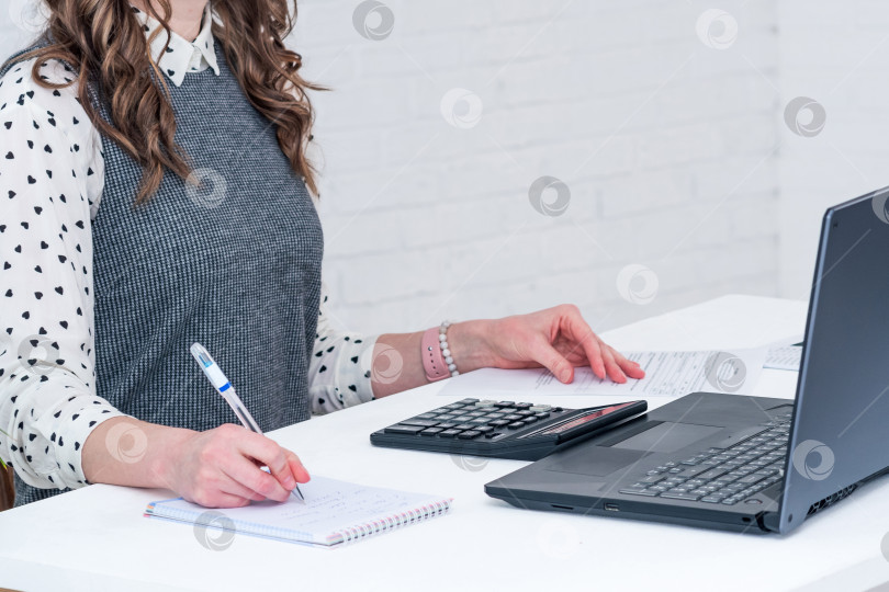 Скачать женщина за столом в помещении работает с документами, калькулятором и ноутбуком фотосток Ozero