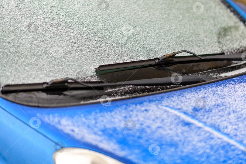 Скачать Автомобильный стеклоочиститель на стекле с намерзшим льдом и снегом в выборочном фокусе. Чистка лобового стекла холодной зимой, поздней осенью. фотосток Ozero