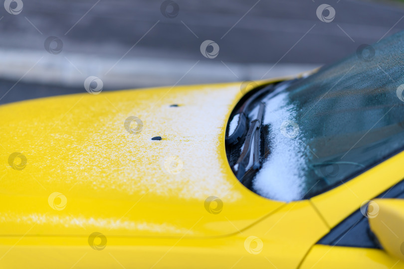 Скачать Переднее стекло и капот желтого автомобиля с намерзшим льдом и снегом в выборочном фокусе. Лобовое стекло в холодную зиму. фотосток Ozero