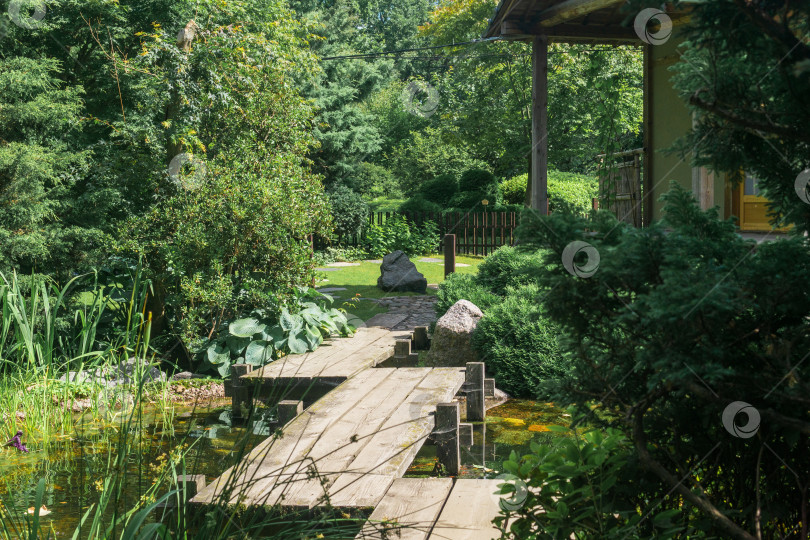 Скачать японский сад с зигзагообразным мостиком через пруд и чайным домиком фотосток Ozero