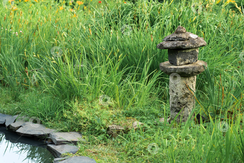 Скачать старый каменный фонарь среди травы на берегу пруда в японском саду фотосток Ozero