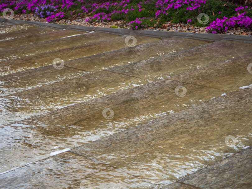 Скачать Вода стекала по ступенькам. Вода стекает по декоративным каменным ступеням дорожки в городском парке фотосток Ozero