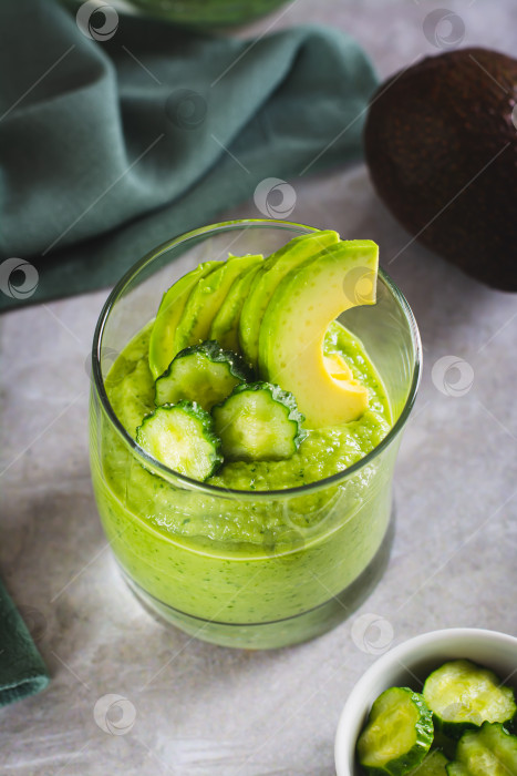 Скачать Полезный напиток из огурцов и авокадо в бокале на столе вертикальный вид фотосток Ozero