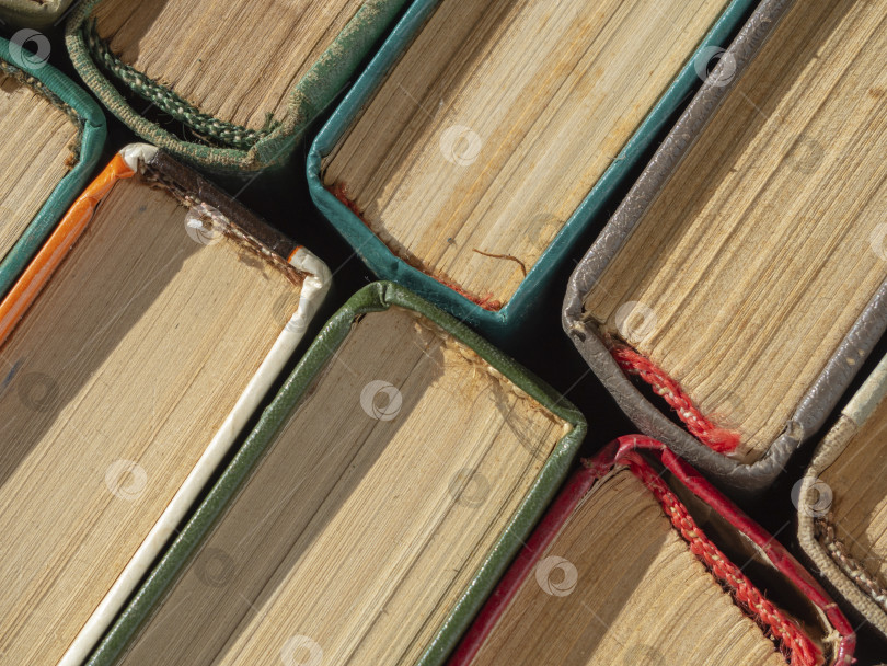 Скачать Множество различных книг в твердом переплете в качестве фона, макросъемка с видом сверху. Многие старые книги сложены стопками по текстуре. Абстракция вертикально стоящих книг, вид сверху на книжные корешки фотосток Ozero